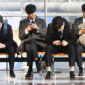 Fyra unga män som tittar på sina mobiltelefoner.
