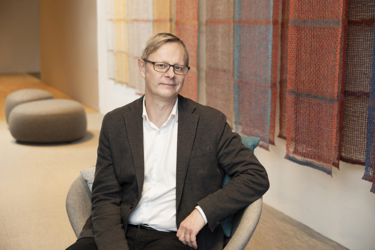 Kuvassa mies istuu toimistoaulassa nojatuolissa.